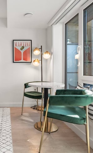 Un coin repas avec une table ronde, deux chaises, un lampadaire et un tableau encadré au mur.