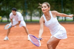 Un court de tennis où les joueurs portent des vêtements blancs.