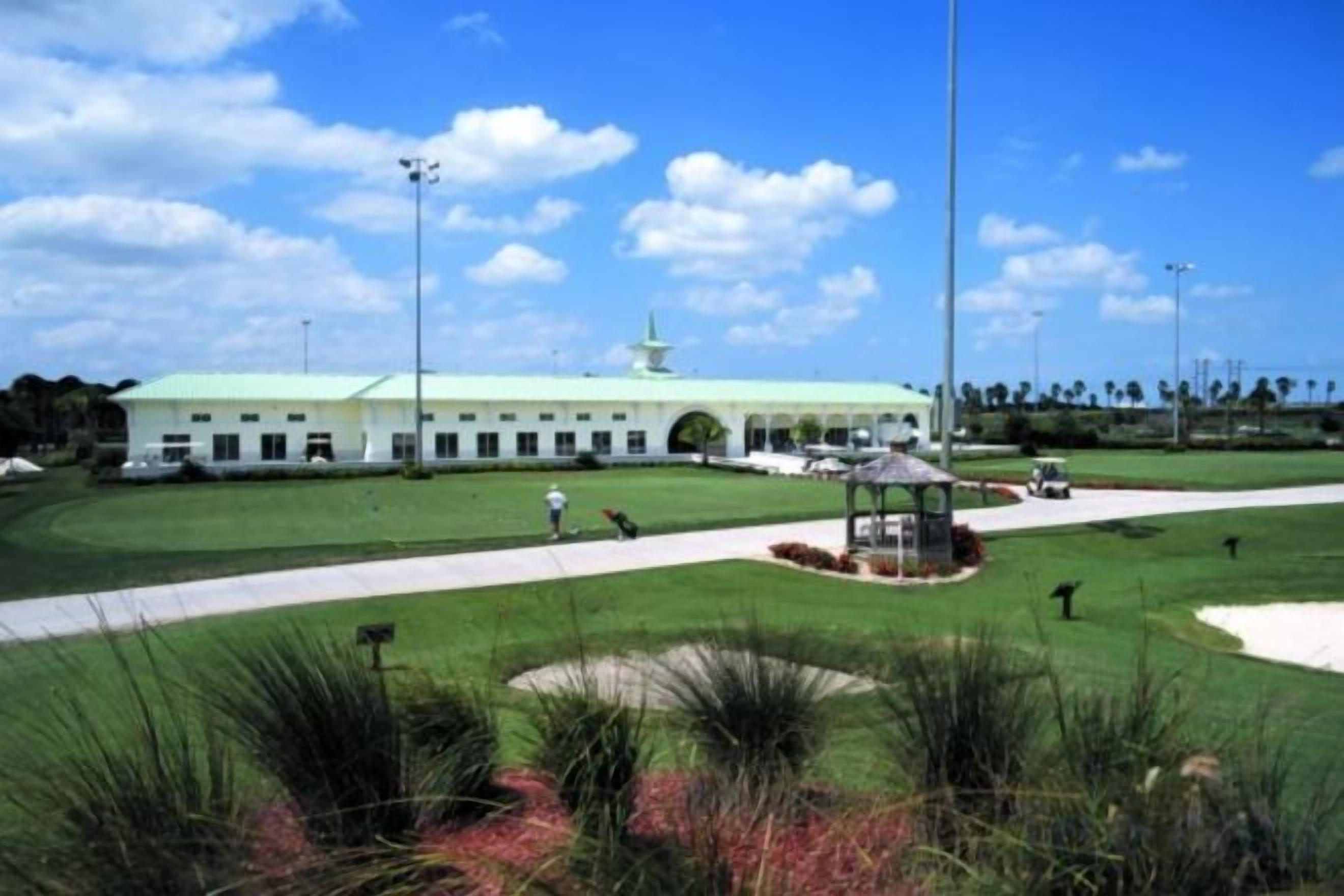 A building with a green roof, a central gazebo, and a well-maintained lawn.