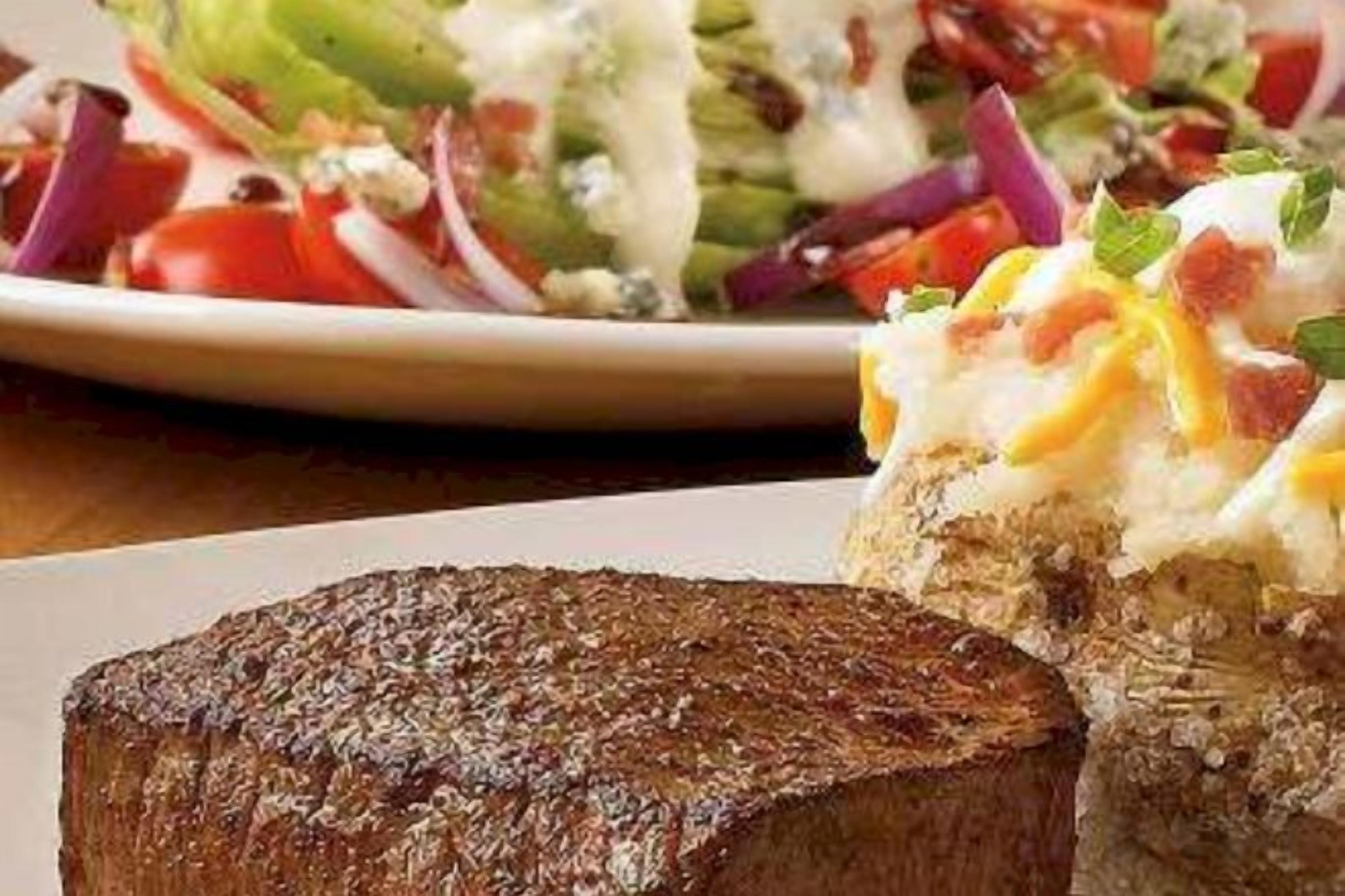 A plate with a grilled steak and a side salad with various vegetables and a creamy dressing.