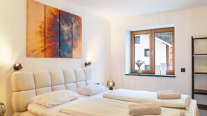 A hotel room with a large bed, a window with a view, and a painting on the wall. - Apartment 'Luisa' with Mountain View, Private Terrace and Wi-Fi (Scharnitz)