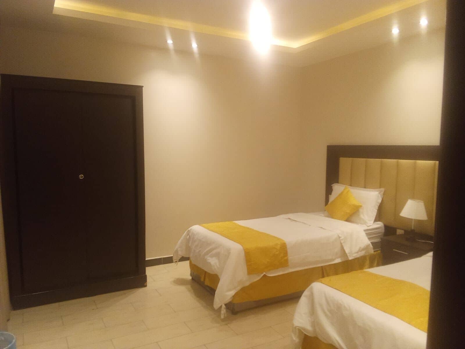 Une chambre d’hôtel avec deux lits, une table de chevet, une lampe et une porte.