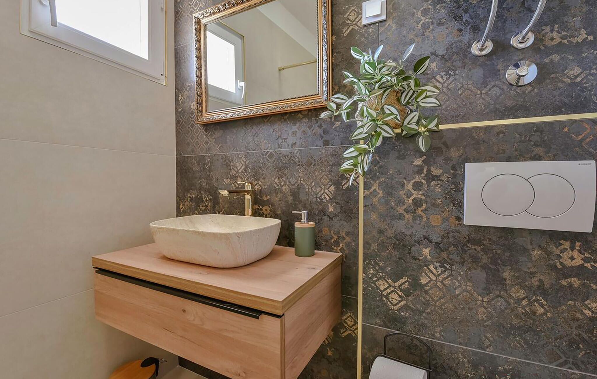Ein Badezimmer mit einem großen Waschbecken, einem Spiegel, einer Pflanze und einer Dusche.