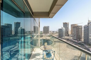 Un balcon situé dans un immeuble de grande hauteur, doté d’une balustrade en verre, et offrant une vue sur la ville.