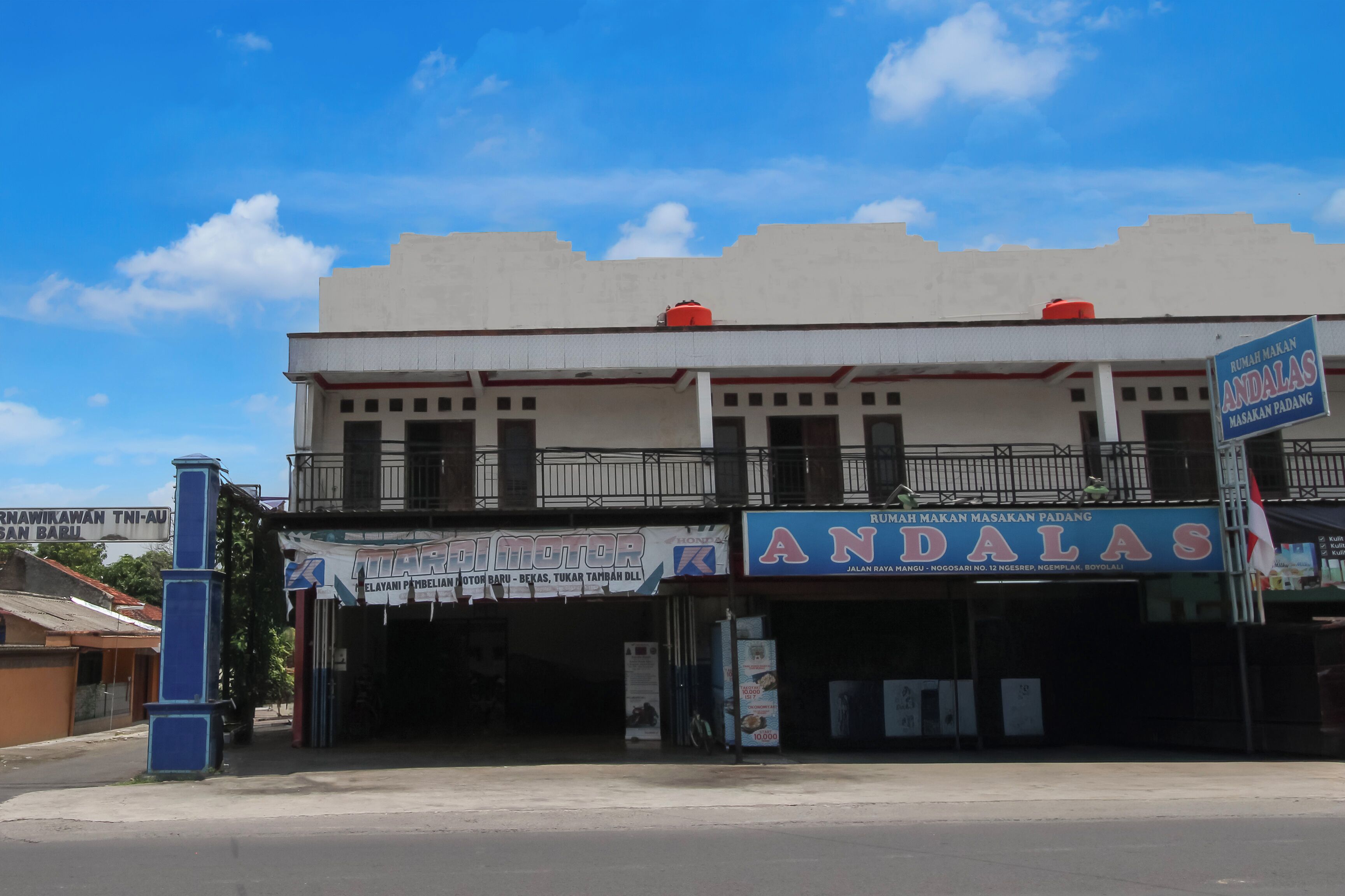 Un immeuble arborant plusieurs enseignes commerciales, notamment « MARIDI MOTOR » et « ANDALAS ».