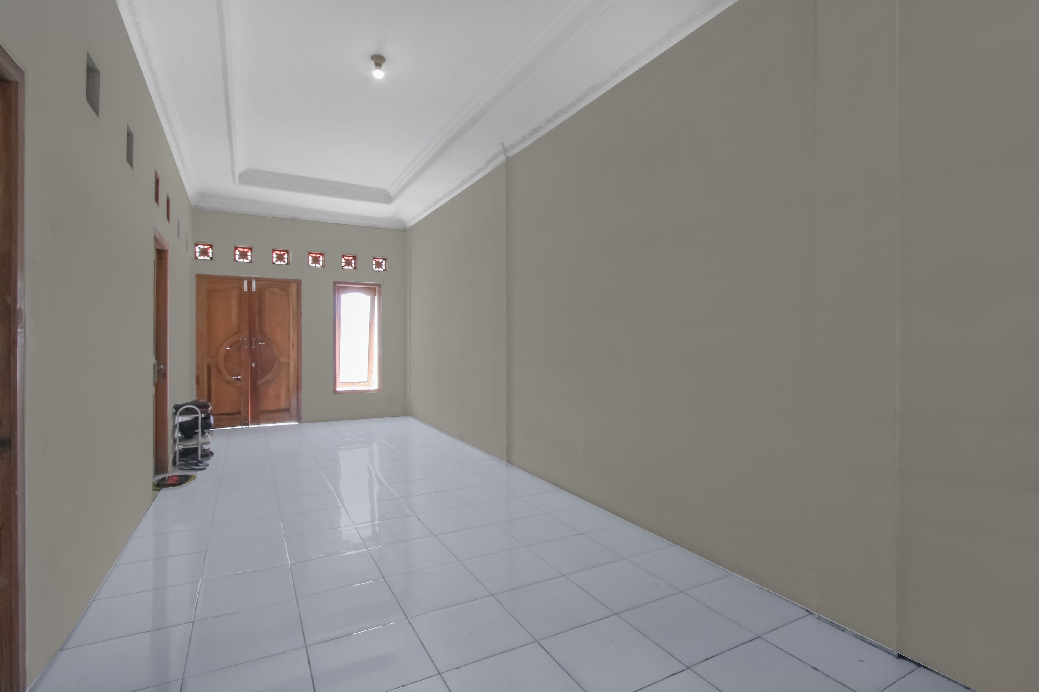 A spacious hallway with a tiled floor, a wooden door, and a small window.