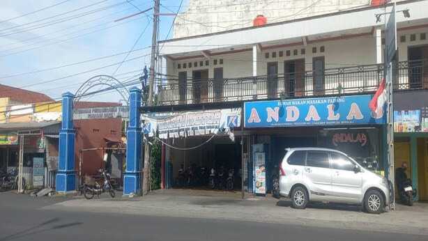 Ein Schaufenster mit einem Schild, auf dem "ANDALAS" steht, und einem weißen Auto davor geparkt.