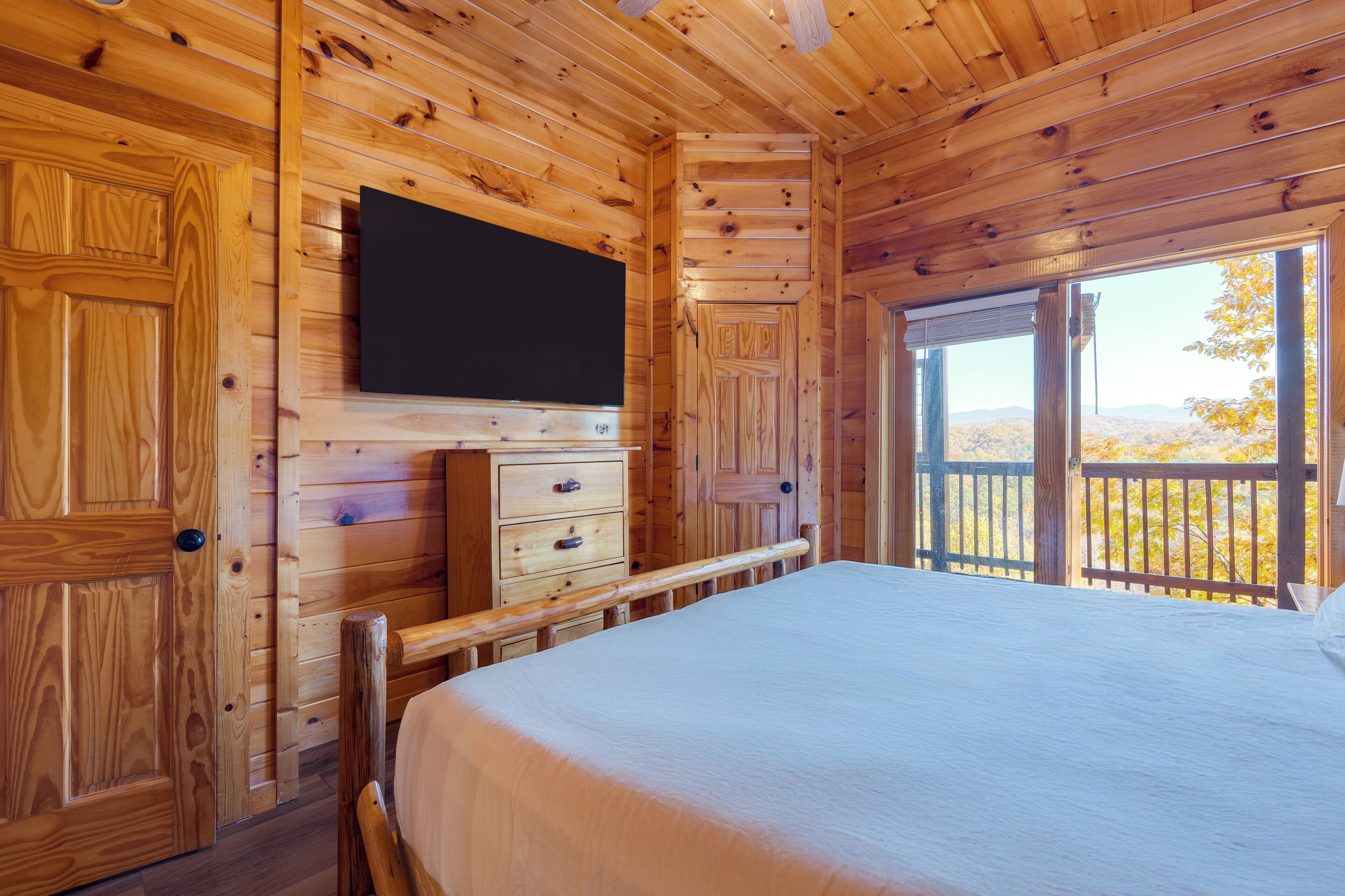 Une chambre dans une cabane en bois, avec un lit, une commode et un téléviseur fixé au mur.