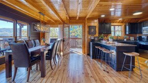 Interior de una cabaña de madera con comedor, cocina y barra.