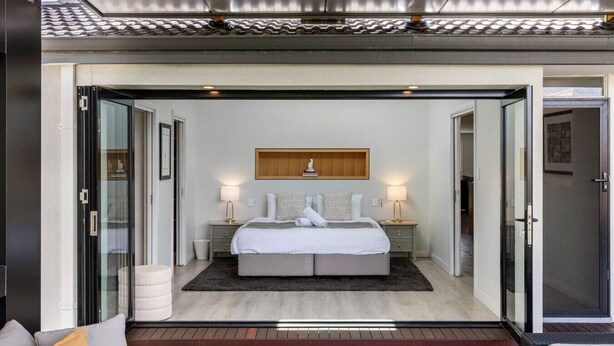 Quarto moderno com cama grande, mesas de cabeceira e cabeceira de madeira.