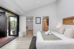 Et moderne soveværelse med en stor seng, et walk-in closet og en skydedør til en patio.