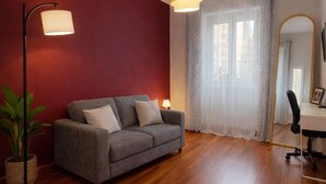 Ein modernes Wohnzimmer mit einem grauen Sofa, einer Stehlampe und einem Spiegel.
