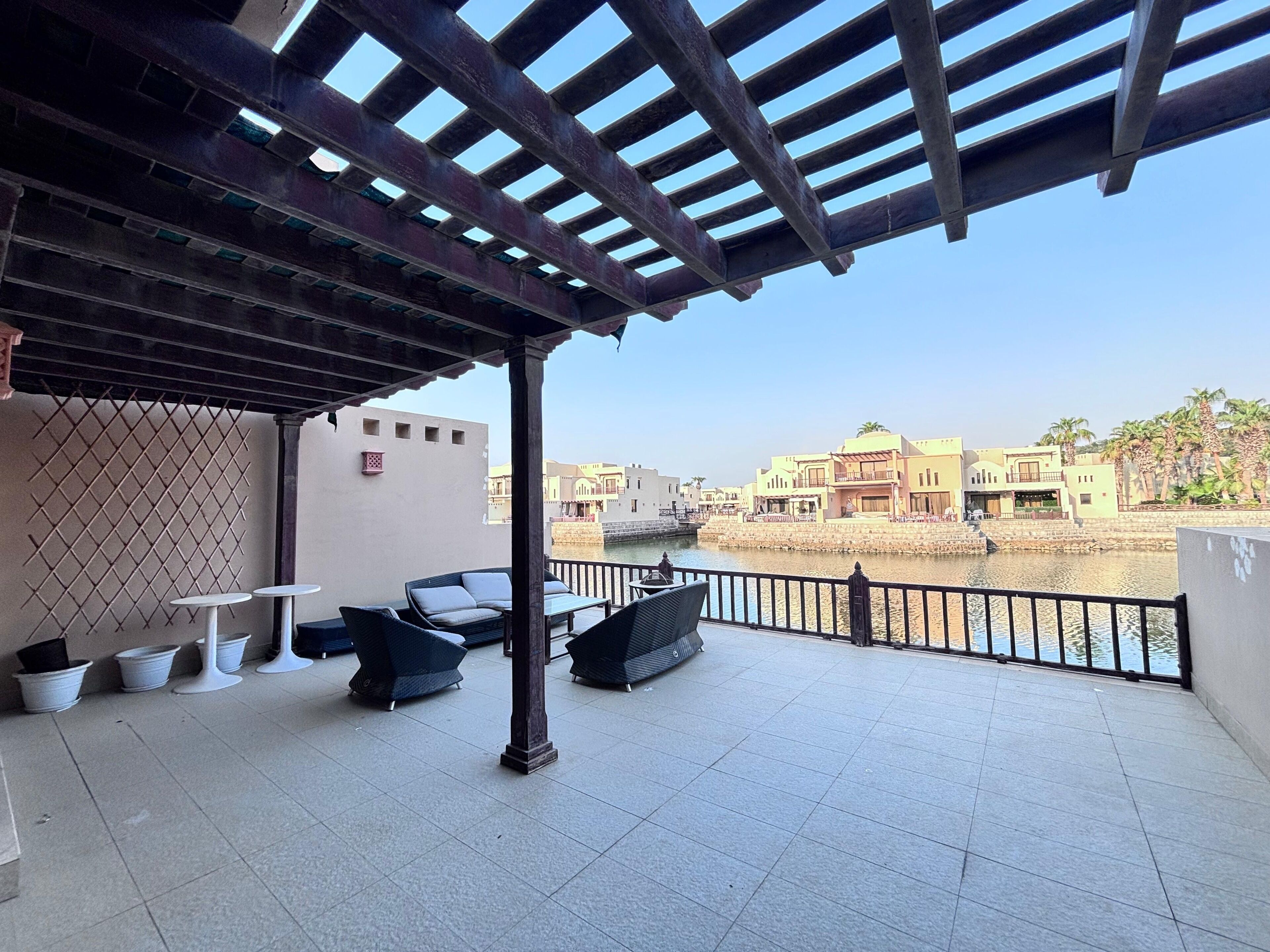 A covered outdoor area with a view of a river and buildings in the background.