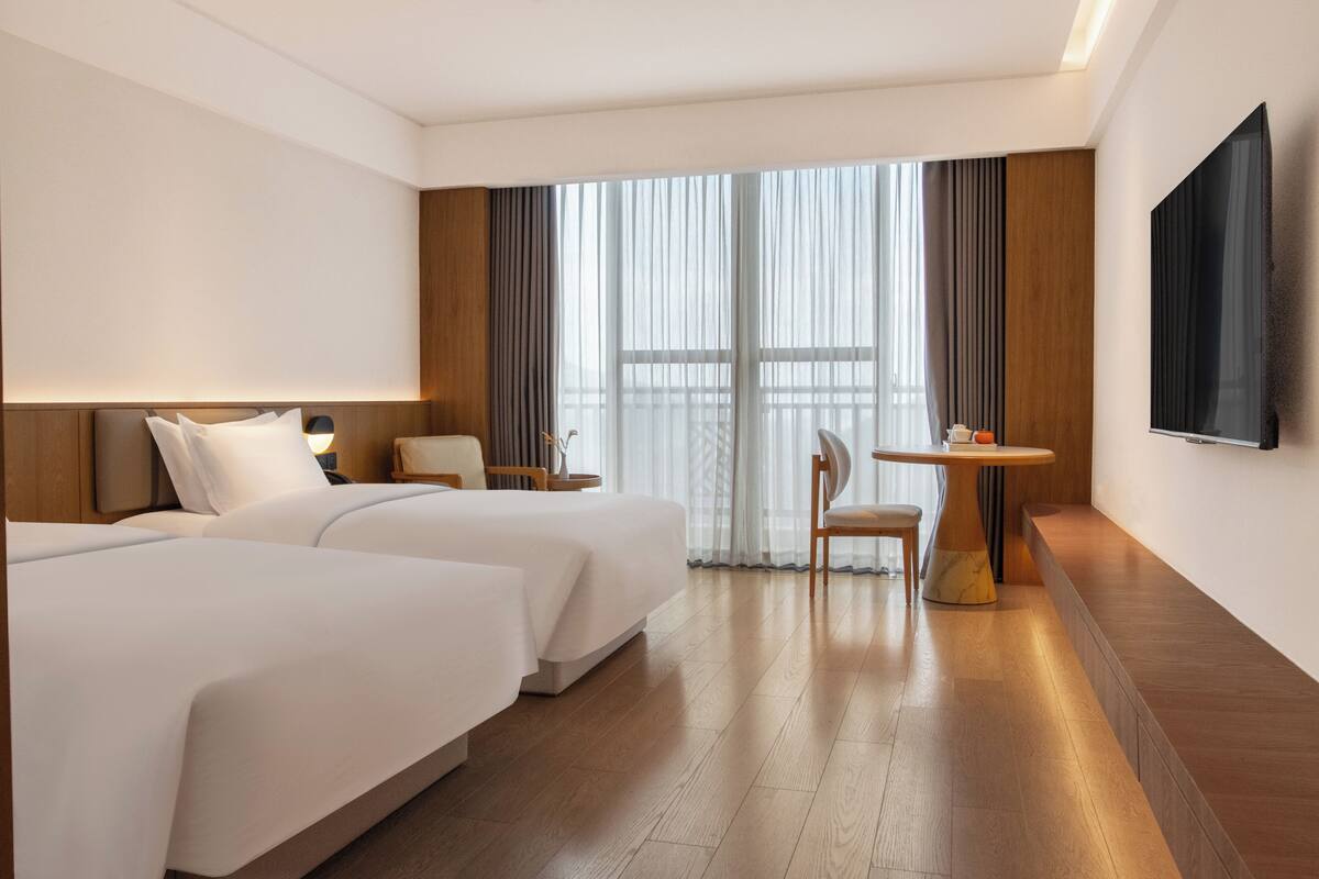Een hotelkamer met twee bedden, een televisie, een kleine tafel en een stoel.