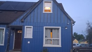 Una casa azul con techo a dos aguas, una puerta principal y dos ventanas.