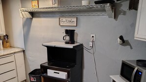 Una cocina compacta equipada con cafetera, microondas y un cubo de basura.