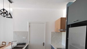 Een moderne keuken met grijze kastjes, een roestvrijstalen koelkast en een houten aanrecht.