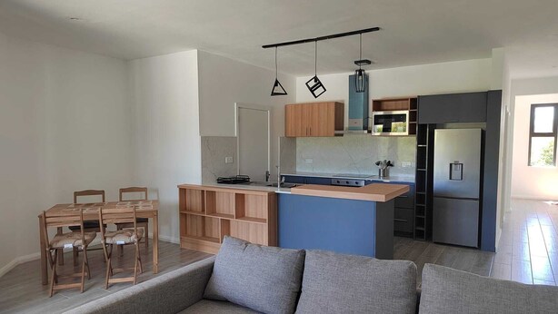 Een moderne keuken met een centraal eiland, houten kastjes en een inbouw-magnetron.