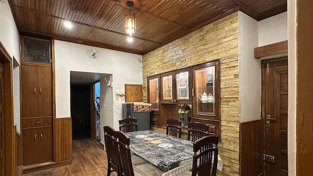 Un espace repas doté d’un plafond en bois, d’un mur en pierre et d’armoires en bois.