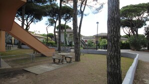 A courtyard with a stone bench, a tree, and a building with a staircase. - Welcoming apartment steps from the beach (Rosolina Mare)