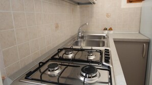 A kitchen with a gas stove, stainless steel sink, and tiled backsplash. - Welcoming apartment steps from the beach (Rosolina Mare)