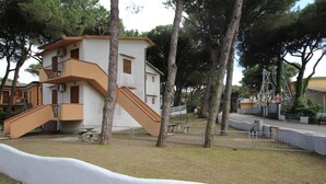 A two-story building with a staircase and a fenced area. - Welcoming apartment steps from the beach (Rosolina Mare)