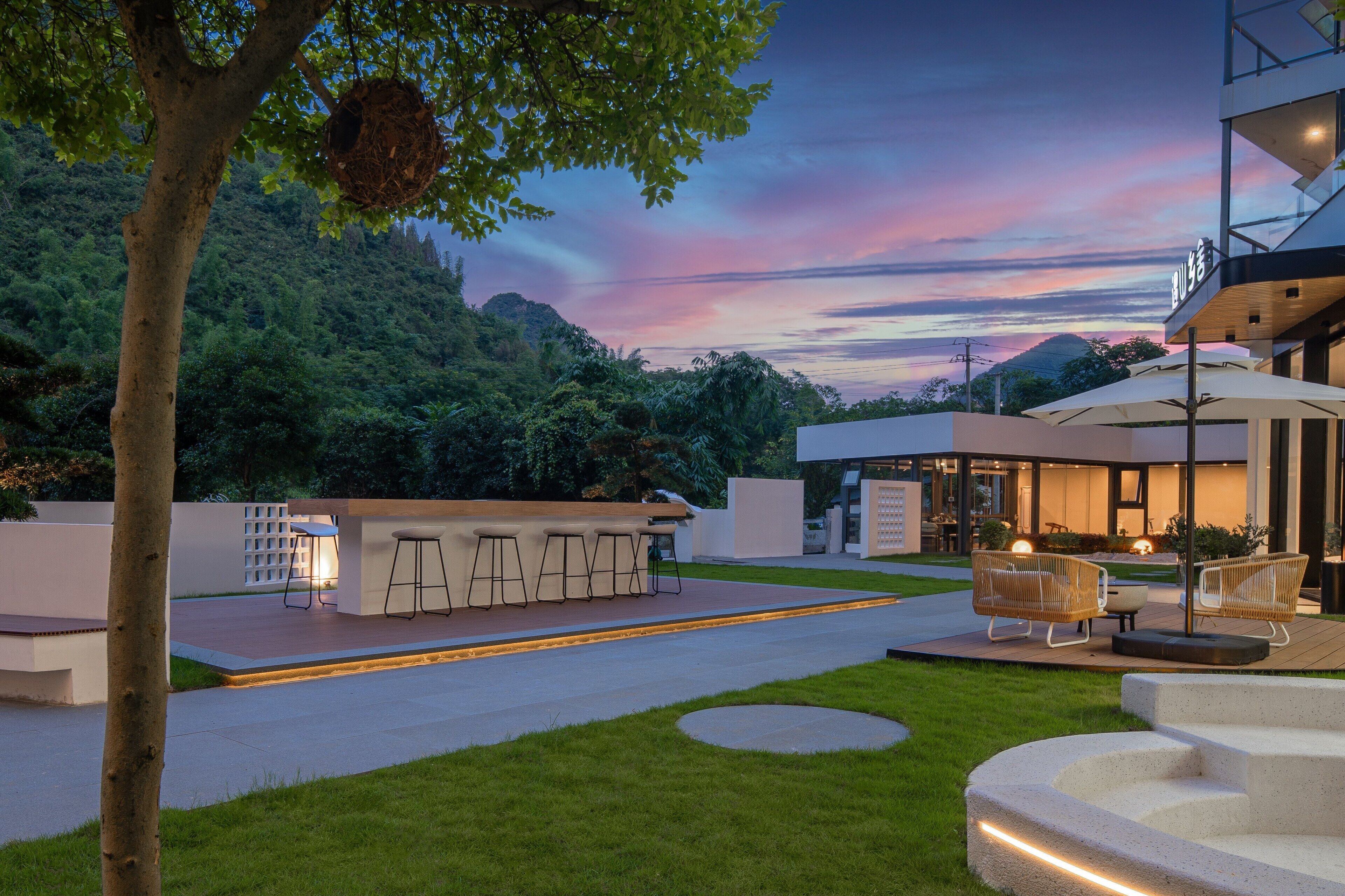 Un espacio exterior moderno con bar, asientos y una escalera.
