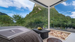 A modern room with a large window overlooking a mountainous landscape. - Karst Scenic Hotel (Guilin)