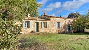 Una casa in pietra con tetto in tegole, un camino e un piccolo giardino antistante.
