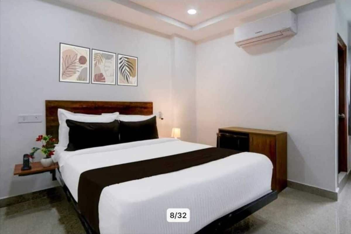 Une chambre d’hôtel avec un lit, une table de chevet, une lampe et des œuvres d’art murales.