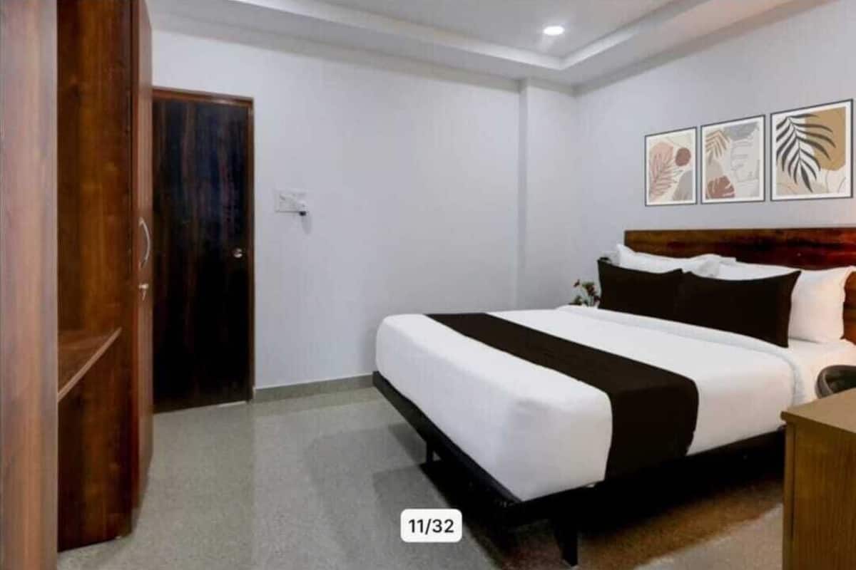 Une chambre d’hôtel avec un lit, une porte en bois et trois œuvres d’art encadrées accrochées au mur.
