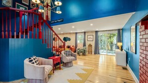 A modern living room with a staircase, wooden flooring, and a view of the outdoors. - Sleeps 13 • Private Sauna • Hot Tub • Game Room (Pocono Lake)