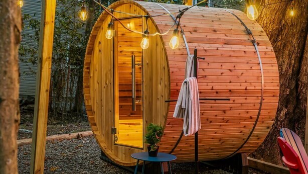 A wooden cylindrical structure with a door, a small table with a plant, and a towel hanging on a hook. - Sleeps 13 • Private Sauna • Hot Tub • Game Room (Pocono Lake)