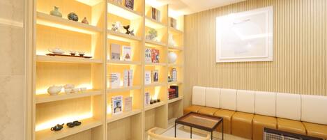 A room with a sofa, a small table, and a bookshelf with books and decorative items.