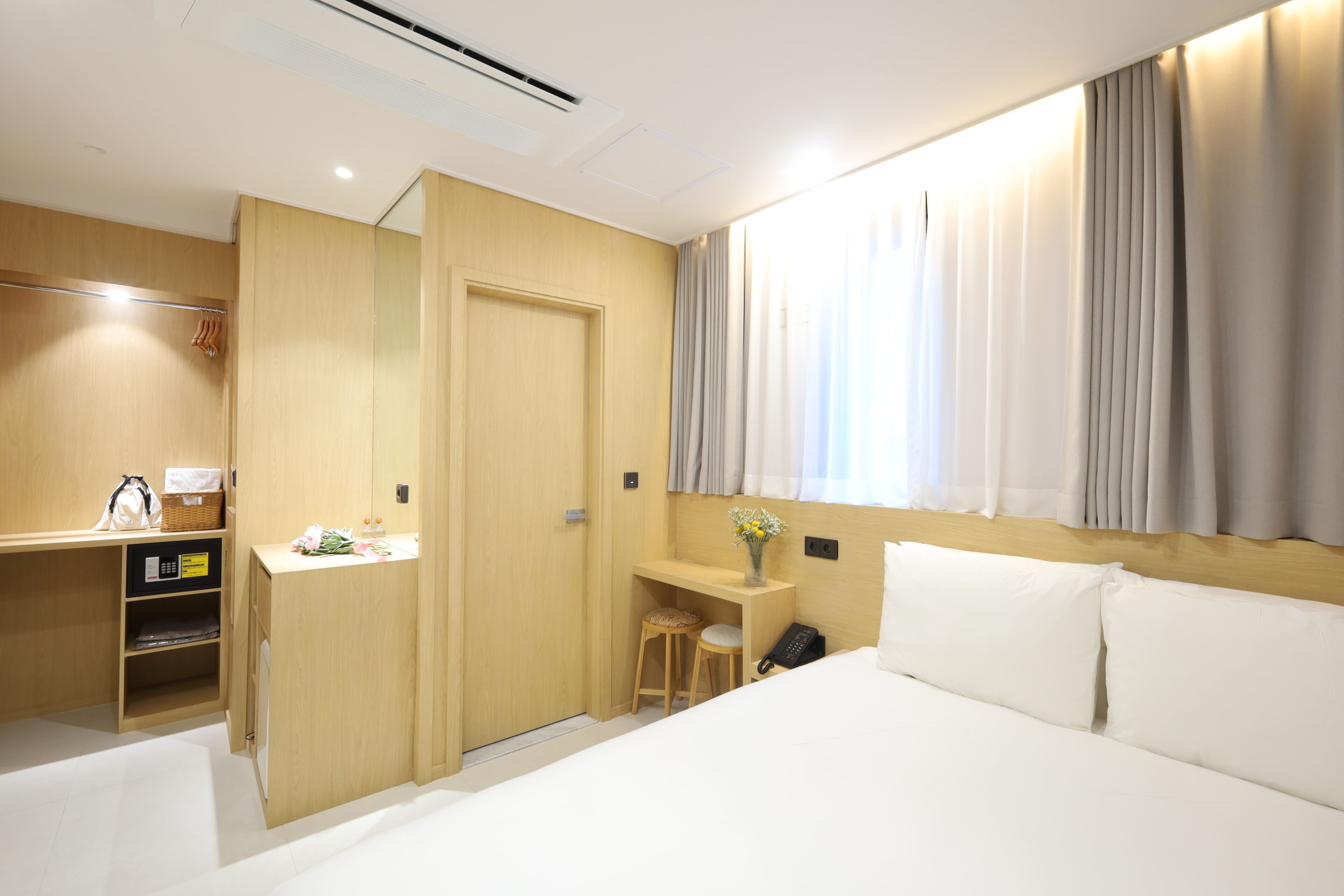 Une chambre d’hôtel équipée d’un lit, d’un bureau, d’une chaise, d’un téléphone, d’un miroir et d’une armoire.