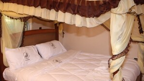 A bed with a canopy, white bedding, and pillows with a logo. - Latahzan guest house (Moyale)