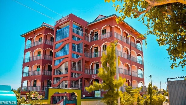 A multi-story building with balconies, a gated entrance, and a clear sky. - Latahzan guest house (Moyale)