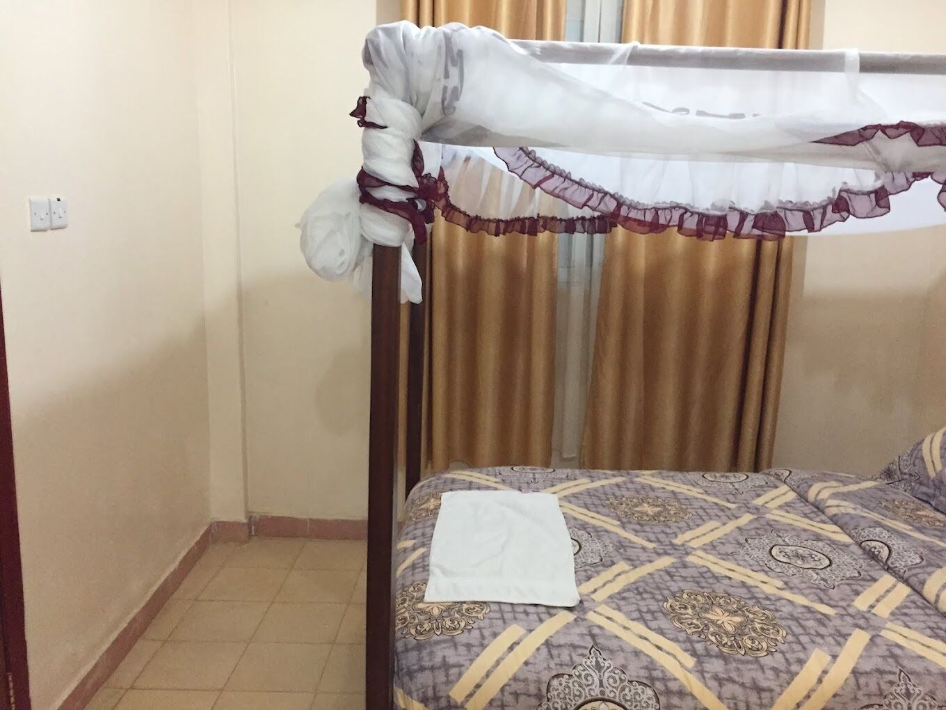 Een kamer met een bed, een gordijn en een stopcontact.