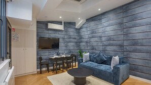 A modern living room with a blue sofa, a round coffee table, and a dining area with chairs and a table. - Superb & New Apartment Saint Germain des Près (Paris)