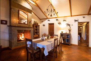 A dining area with a fireplace, wooden beams, and a chandelier. - The Cottage is Situated on a Farm in Laikipia 32km From Nanyuki - 2330 (Ethi)