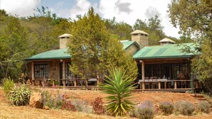A rustic lodge with two main buildings, each featuring a green roof and wooden porch. - The Cottage is Situated on a Farm in Laikipia 32km From Nanyuki - 2330 (Ethi)