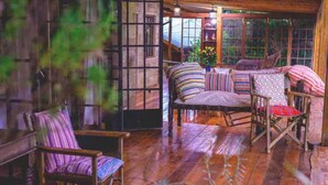 A cozy room with wooden floors, a cushioned seating area, and a large window with a view of greenery. - The Cottage is Situated on a Farm in Laikipia 32km From Nanyuki - 2330 (Ethi)