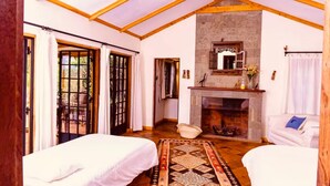 A cozy room with a stone fireplace, wooden beams, and a bed with a patterned rug. - The Cottage is Situated on a Farm in Laikipia 32km From Nanyuki - 2330 (Ethi)