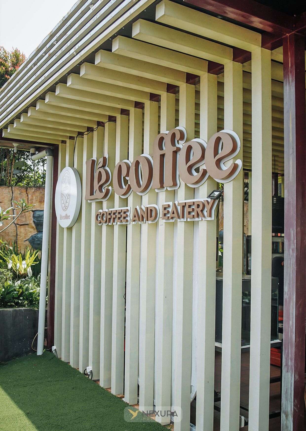 A sign for 'LeCoffee Coffee and Eatery' with a logo and vertical wooden slats.