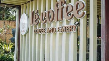 A sign for 'LeCoffee Coffee and Eatery' with a logo and vertical wooden slats.