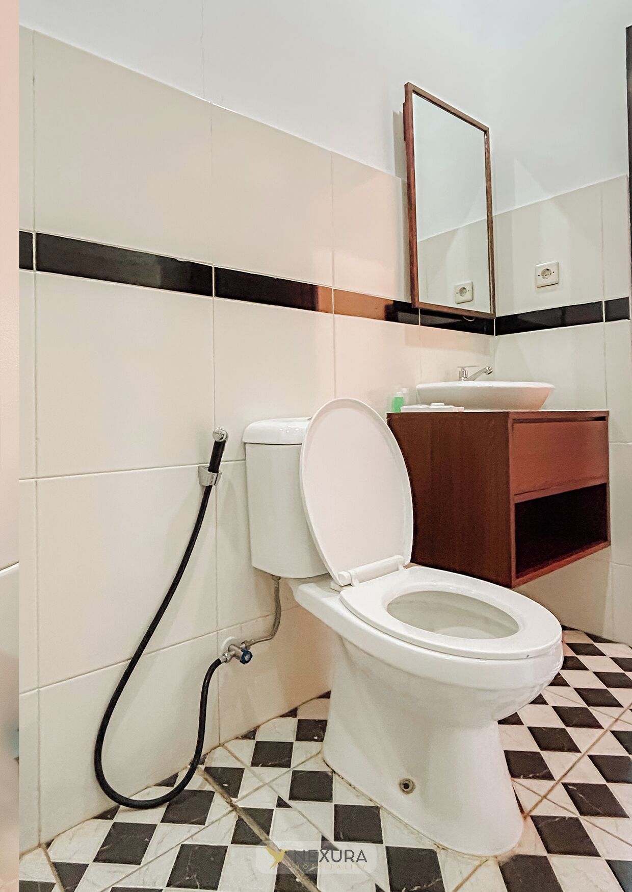 A bathroom with a toilet, sink, and mirror.