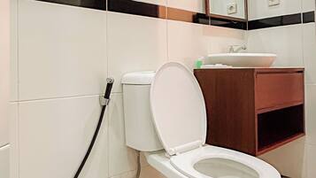 Een badkamer met toilet, wastafel en spiegel.
