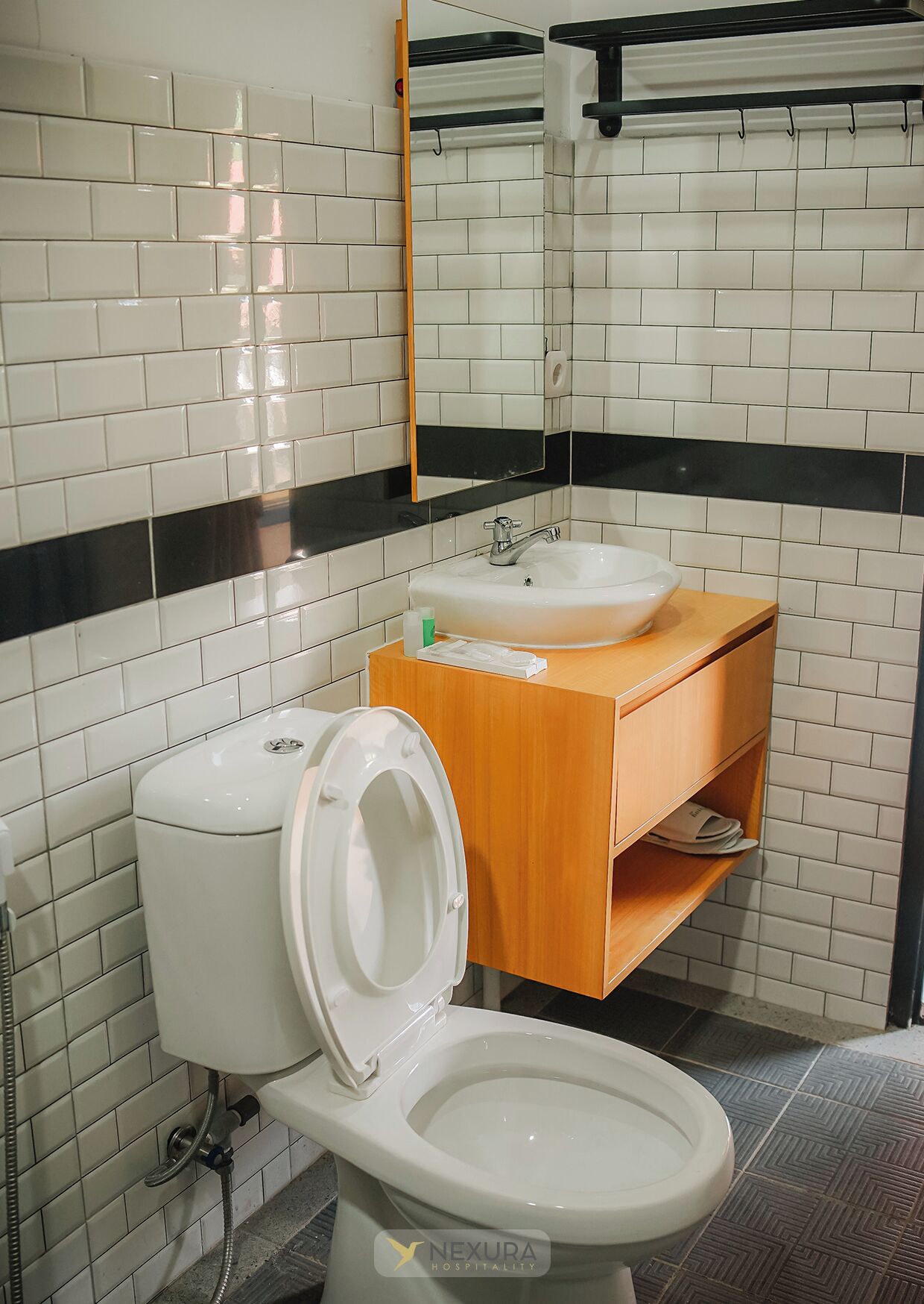 A bathroom with a white toilet, a wooden vanity with a sink, and a mirror above the sink.