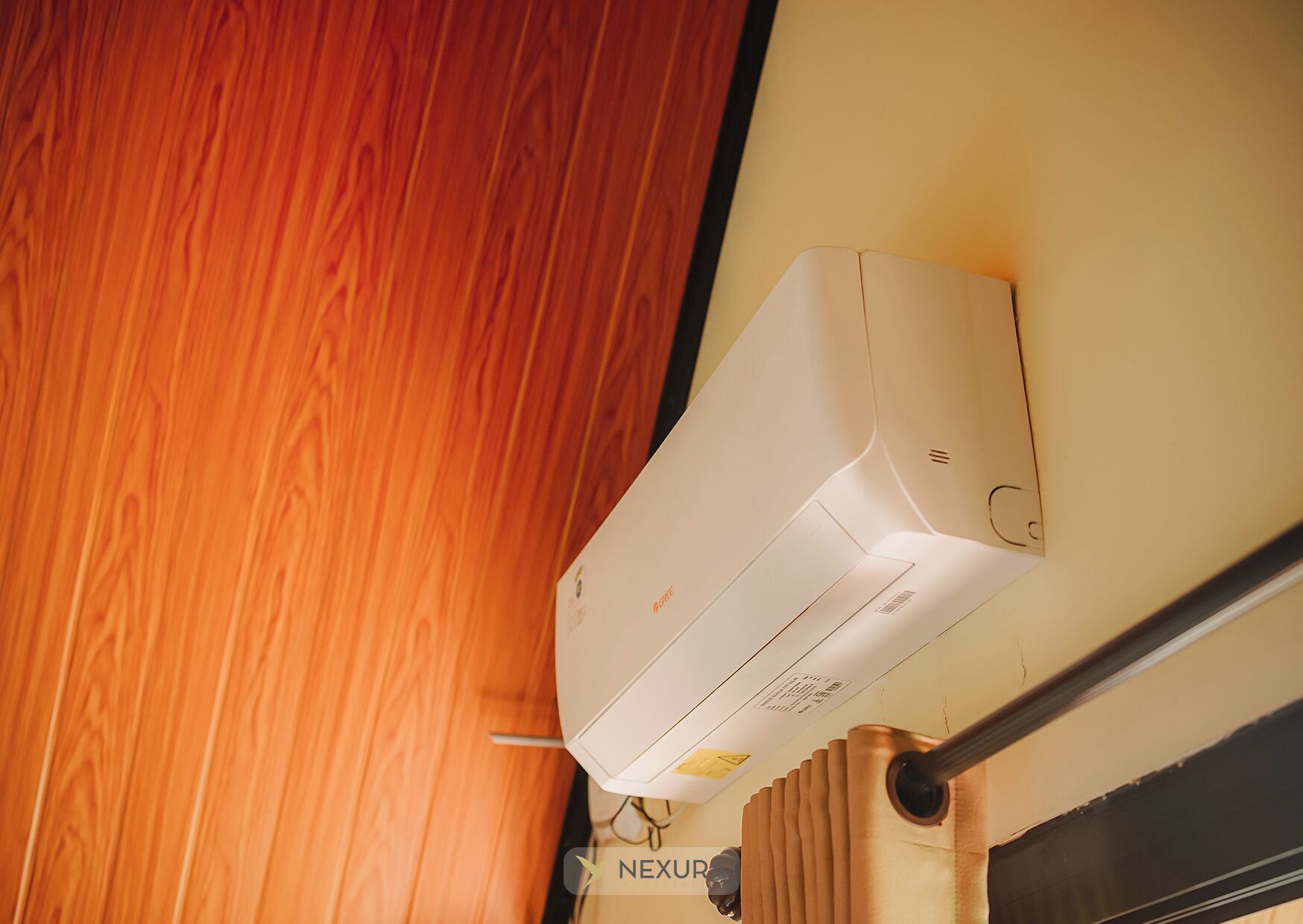 Eine weiße Klimaanlage an einer Wand montiert, neben einer Holzverkleidung und einem Metallträger.