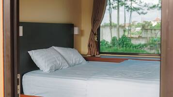 Ein Schlafzimmer mit Bett, einem Fenster mit Vorhängen und einer Pendelleuchte.